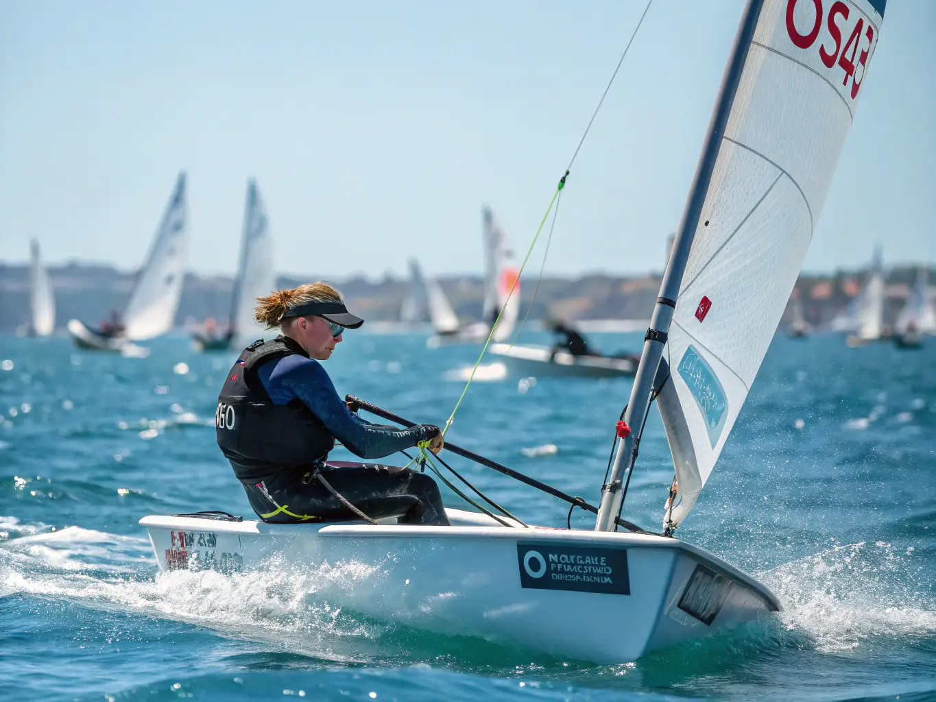 An image of adults participating in an advanced sailing course, navigating a sailboat through more challenging waters, with the coastline in the background.